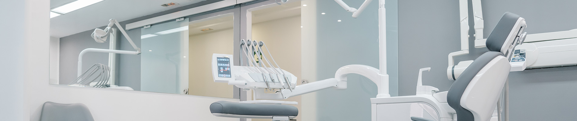 The image shows a modern dental clinic interior with various pieces of equipment, including a dental chair and an X-ray machine.