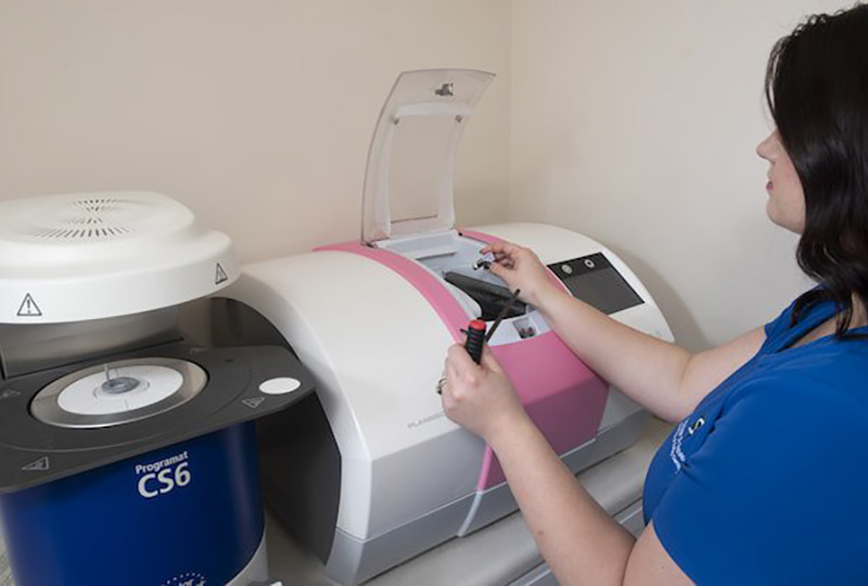 A woman operating a large-scale printer with a pink label.