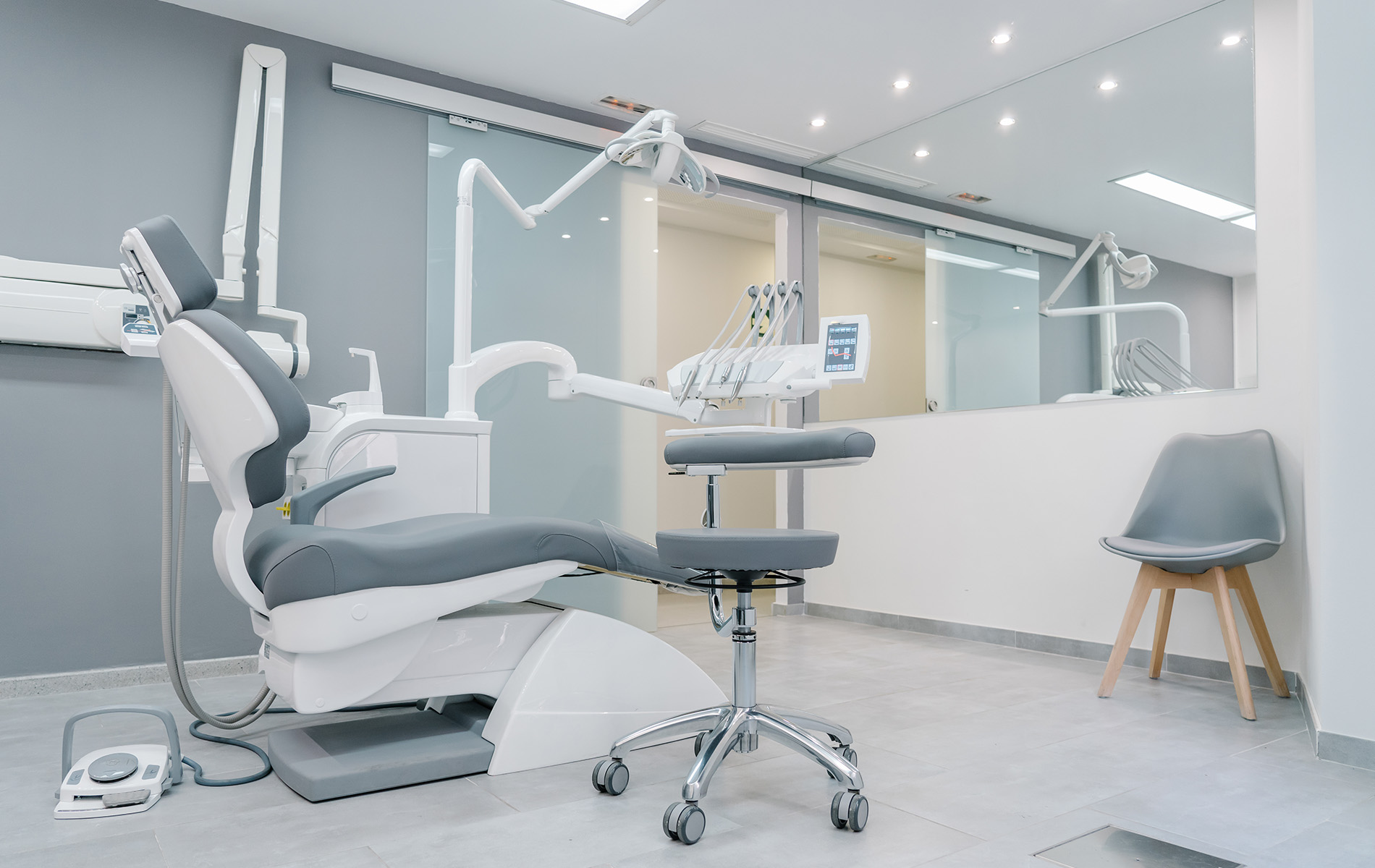The image displays a modern dental office interior with a dental chair, equipment, and a clean, professional environment.
