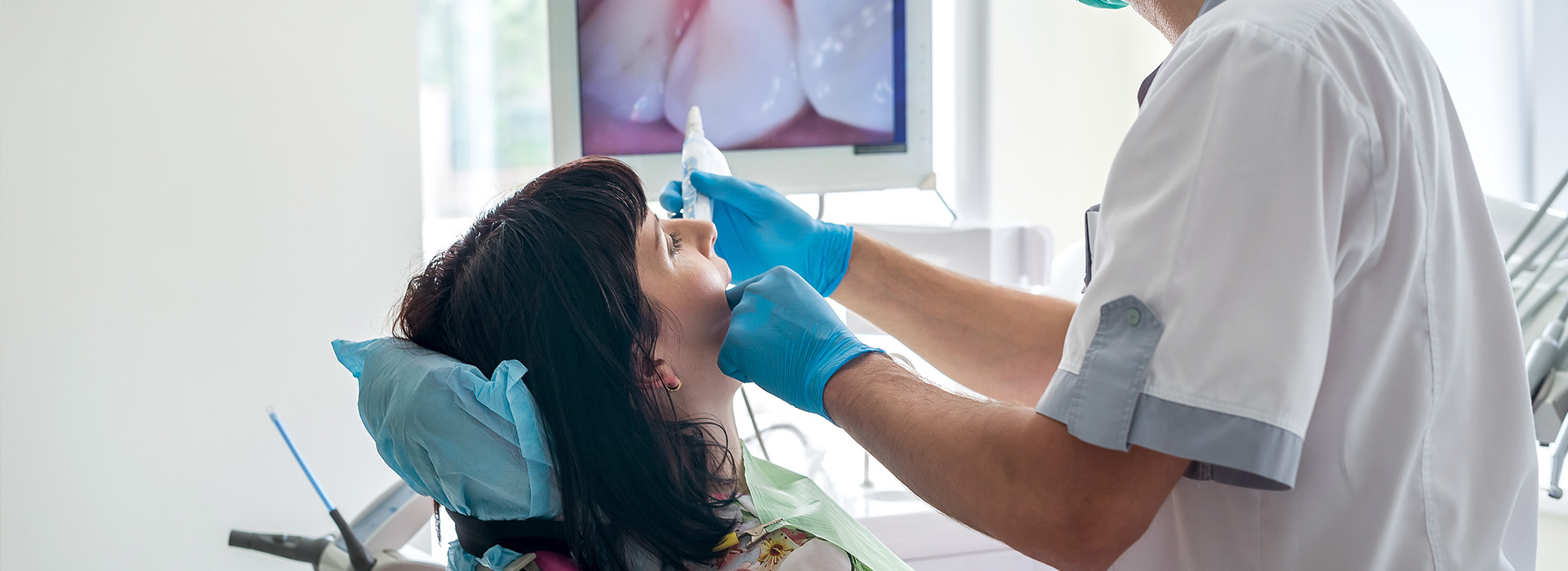 A dental professional performing oral care on a patient with blue gloves.
