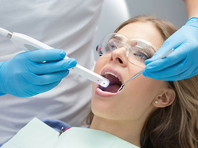 The image shows a dental professional using a device to clean a patient s teeth during a dental procedure.
